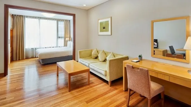 Somerset Palace Seoul 的 1-Bedroom Deluxe 内,卧室旁的沙发、茶几和书桌。