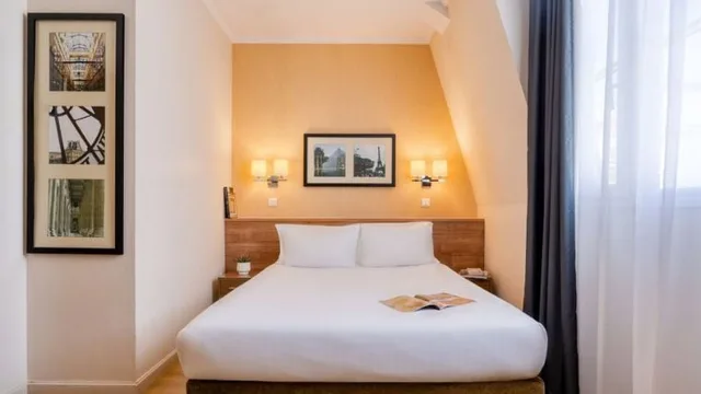 Double bed and framed pictures in a Studio at Citadines Saint-Germain-des-Prés Paris.